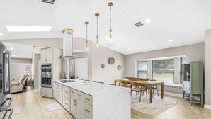 Una cocina moderna con una isla central, electrodomésticos integrados e iluminación colgante.