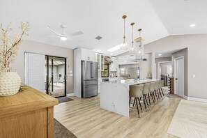 A modern kitchen with a central island, bar stools, and a ceiling fan. - Gorgeous 4 Bedroom Home with Private Pool and Full Kitchen in Rotonda West (Rotonda West)