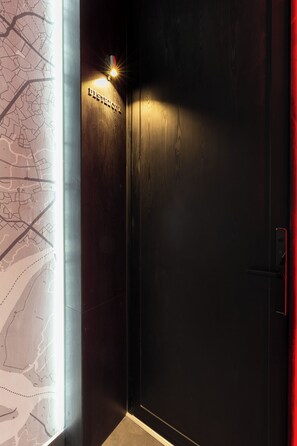 A dark wooden door with a map on the adjacent wall and a small illuminated sign above the door. - Neo Red Studio @ Saigon's alley with Rooftop Onsen (Thành phố Hồ Chí Minh)