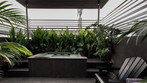 Eine Dachterrasse mit moderner Bar, üppigen Grünpflanzen und einer Sitzgruppe.