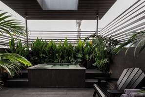A rooftop terrace with a modern bar area, lush green plants, and a seating arrangement. - Neo Red Studio @ Saigon's alley with Rooftop Onsen (Thành phố Hồ Chí Minh)