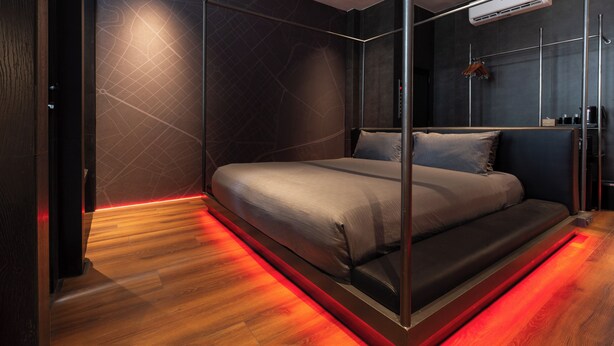 Ein modernes Schlafzimmer mit einem Kapellenbett aus Glas, Holzboden und einer Wandgestaltung mit Stadtansicht.
