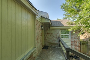 A narrow outdoor corridor with a brick wall, a wooden fence, and a small window. - The Village 3BR (The Village)