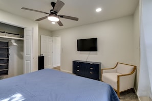 A bedroom with a bed, a ceiling fan, a TV, a chair, and a wardrobe. - The Village 3BR (The Village)