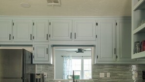 A kitchen with light blue cabinets, a stainless steel refrigerator, a dishwasher, and a tiled backsplash. - The Village 3BR (The Village)