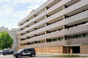 Eine mehrgeschossige Parkgarage mit modernem Design, ausgestattet mit mehreren Balkonen und wolkenlosem Himmel.