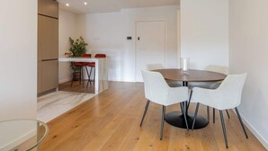 Ein zeitgemäßer Essbereich mit einem runden Tisch, vier grauen Stühlen und einem Holzboden.