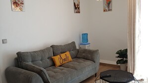 A living room with a grey sofa, a yellow pillow, a hexagonal coffee table with a plant, and a geometric floor lamp. - AirbnbsbyElsie (Ruiru)