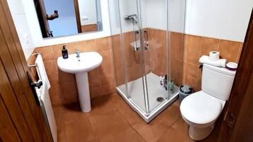 A bathroom with a glass shower enclosure, a pedestal sink, and a toilet.