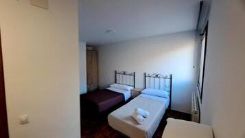 Una camera d'albergo piccola e singola, con due letti, un termosifone e una finestra.