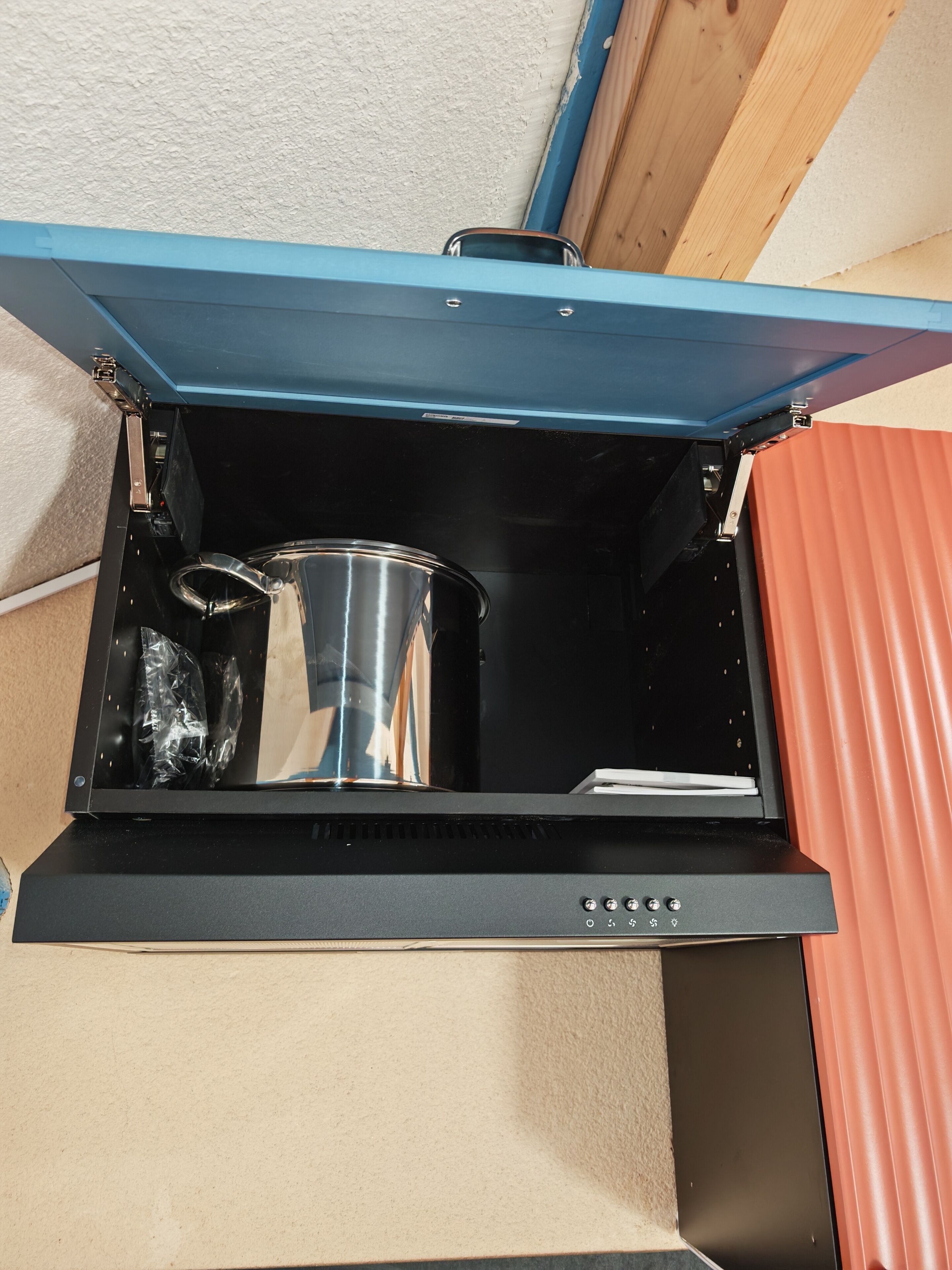 A kitchen with a built-in oven and a stainless steel pot inside.