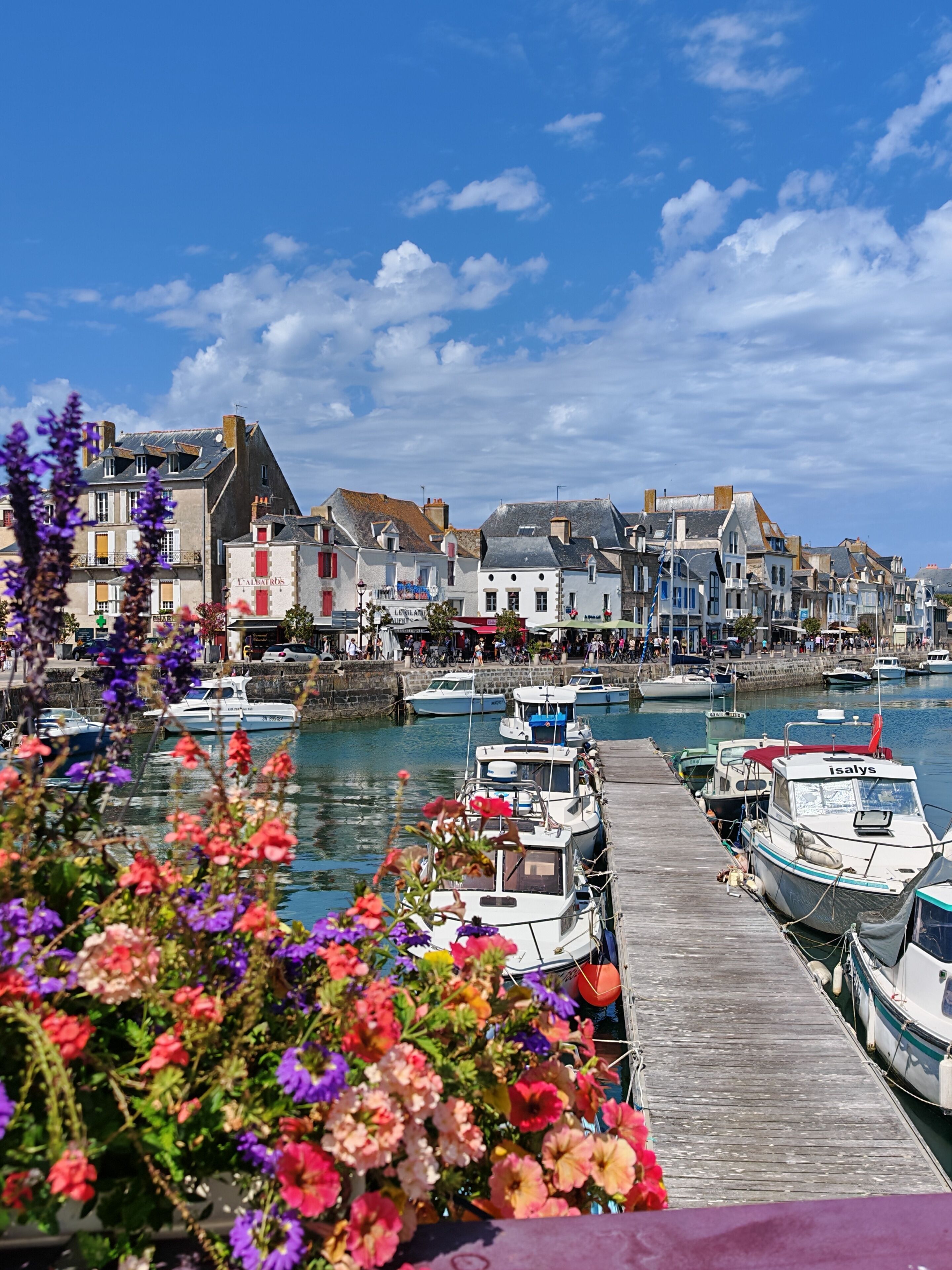 A harbor with boats docked, a wooden pier, and buildings with signage.