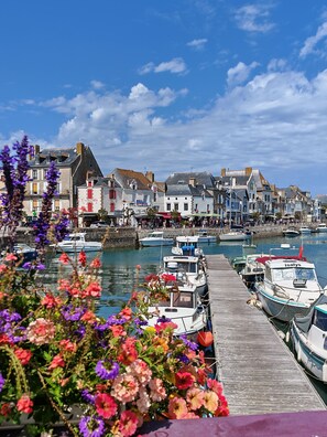 A harbor with boats docked, a wooden pier, and buildings with signage. - The Blue Anchor, a beautiful apartment near the harbor (Le Croisic)