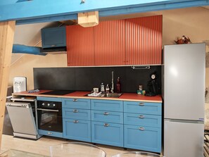 A compact kitchen with a refrigerator, stove, sink, and blue cabinets. - The Blue Anchor, a beautiful apartment near the harbor (Le Croisic)