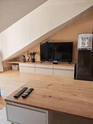 Eine moderne Küche mit Holzarbeitsplatte, einem schwarzen Kühlschrank, einem Fernseher und einer Topfpflanze.