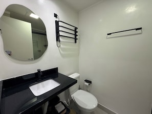 A bathroom with a white sink, toilet, and a mirror. - Studio apartment - the comfortable side of the force (São Paulo)