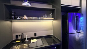 Une cuisine moderne équipée d’un four à micro-ondes encastré, d’un réfrigérateur en acier inoxydable et d’une étagère où sont exposées des figurines de Star Wars.