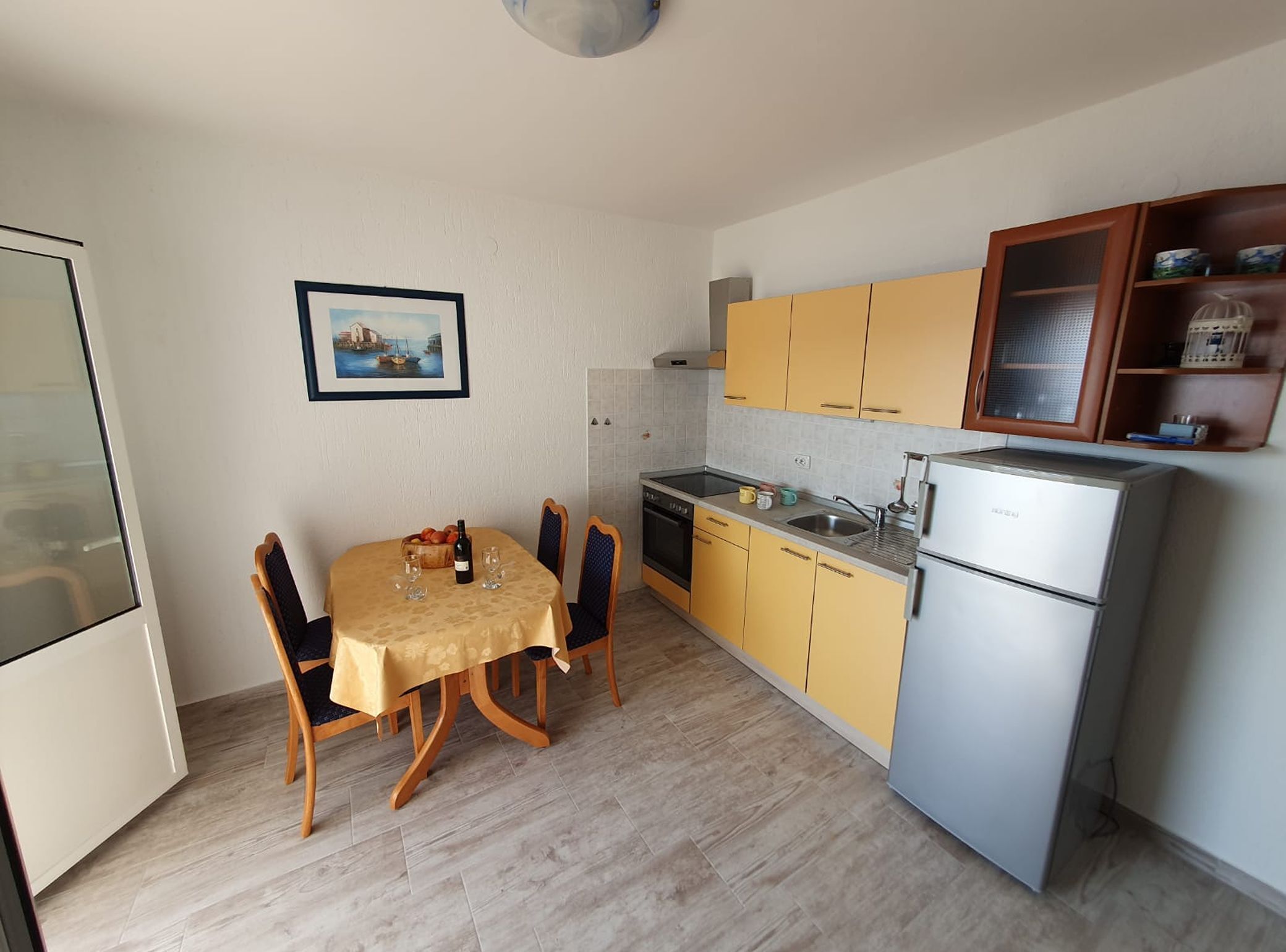 A compact kitchen with a dining area, a refrigerator, and a small cabinet with items on the countertop.