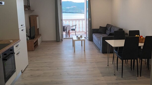 Una sala de estar moderna con sofá, mesa de comedor, sillas y una cocina equipada.