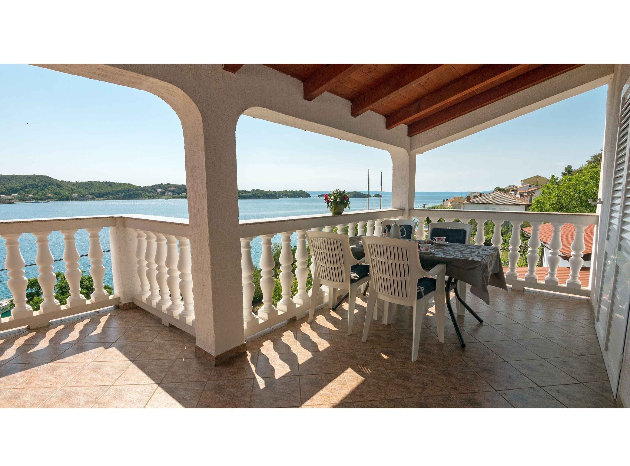 A covered outdoor seating area with a view of a lake and hills.