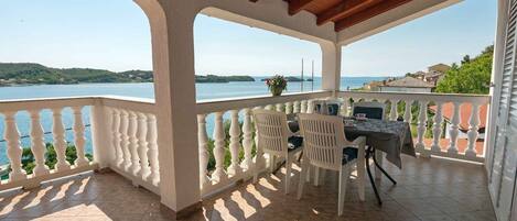 A covered outdoor seating area with a view of a lake and hills.
