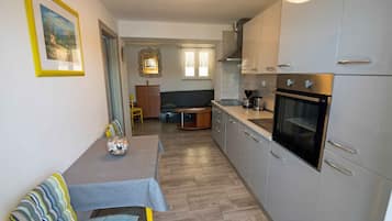 Una cocina compacta con electrodomésticos modernos, un rincón comedor con sofá y una mesita pequeña.