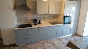 Una cocina moderna con armarios grises, una campana extractora de acero inoxidable, un horno empotrado y una cafetera.