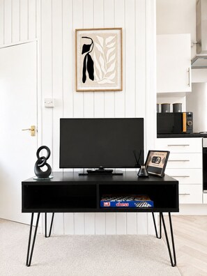 A modern kitchen with a black TV stand, a framed artwork, and a chess set on the counter.