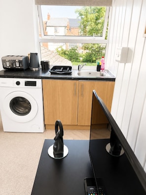 A compact kitchen with a washing machine, a toaster, a kettle, and a sink. - Lamani Homes | Cosy Nest Coventry | Stylish Studio Near City Centre ⭐ (Coventry)