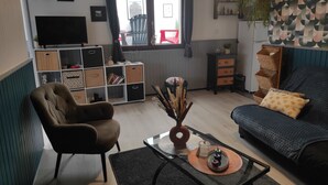 Ein Wohnzimmer mit einer Couch, einem Sessel, einem Couchtisch und einem Fernseher.