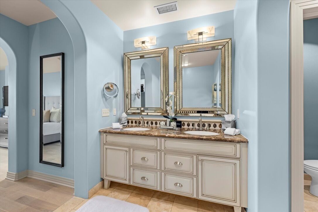 A bathroom with a vanity, two mirrors, and a sink.
