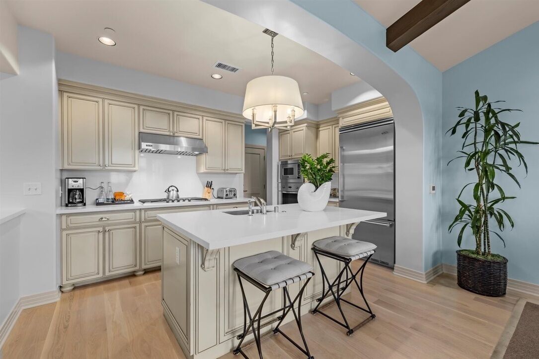 A modern kitchen with a central island, stainless steel appliances, and a hanging light fixture.
