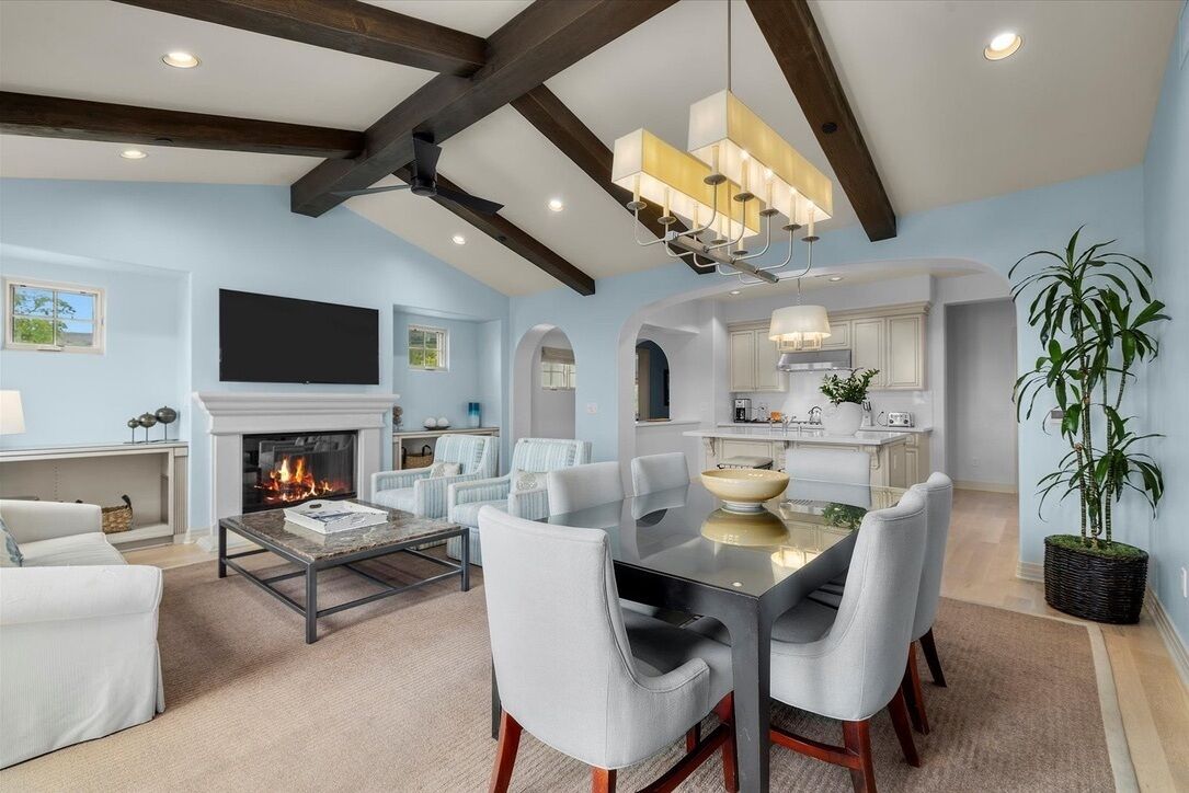A modern living room with a fireplace, dining area, and kitchen.