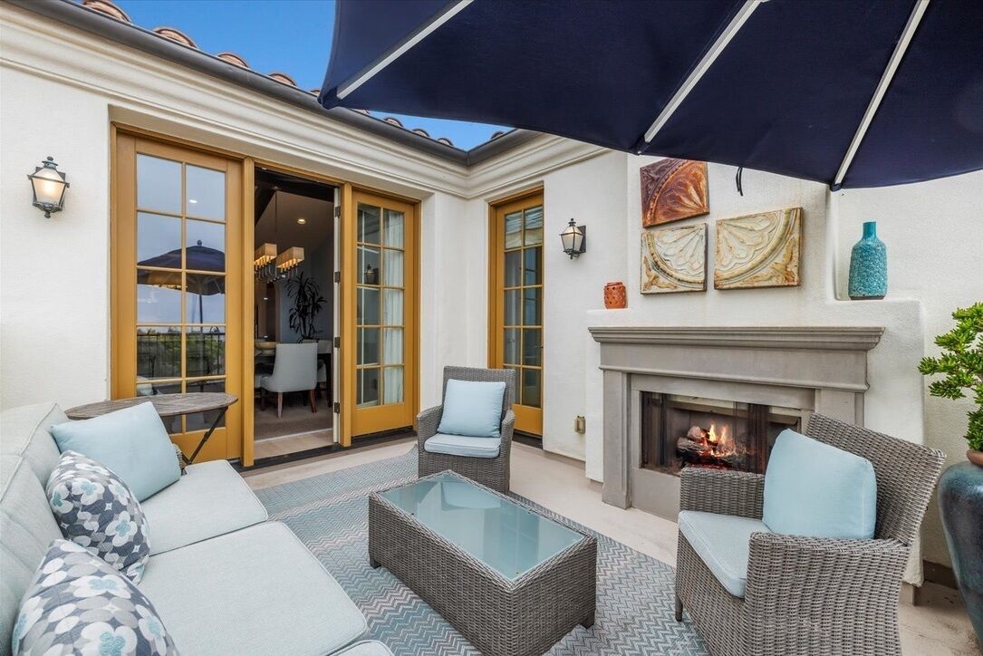 Eine Terrasse mit Korbmöbeln, einem Glastisch und einem Kamin.