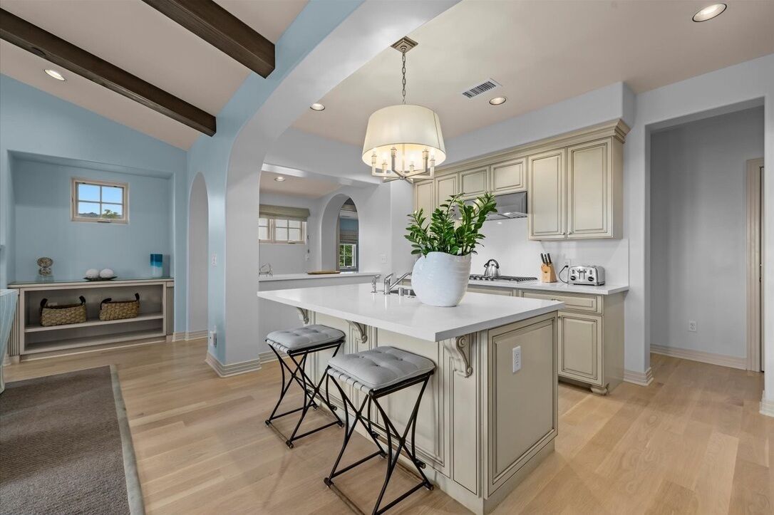 A modern kitchen with a large island, pendant lighting, and bar stools.