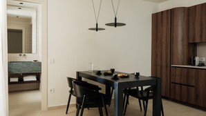 Una cuina moderna amb armaris de fusta fosca, una taula de dinar negra i quatre cadires, i llums penjants.