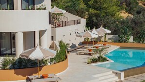 Un hotel modern amb piscina, gandules i ombrelles.
