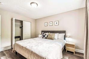 A bedroom with a bed, bedside table, nightstand, wardrobe, and a ceiling light. - S Tampa 3BR | Hot Tub, Fire Pit, Near MacDill (Tampa)