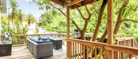 A wooden deck with outdoor furniture, surrounded by lush greenery and trees.