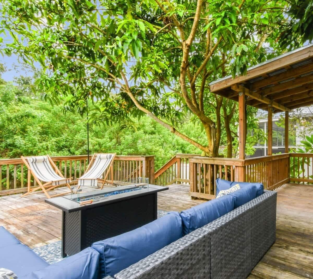 Une terrasse en bois avec des sièges d’extérieur, une pergola et une végétation luxuriante.