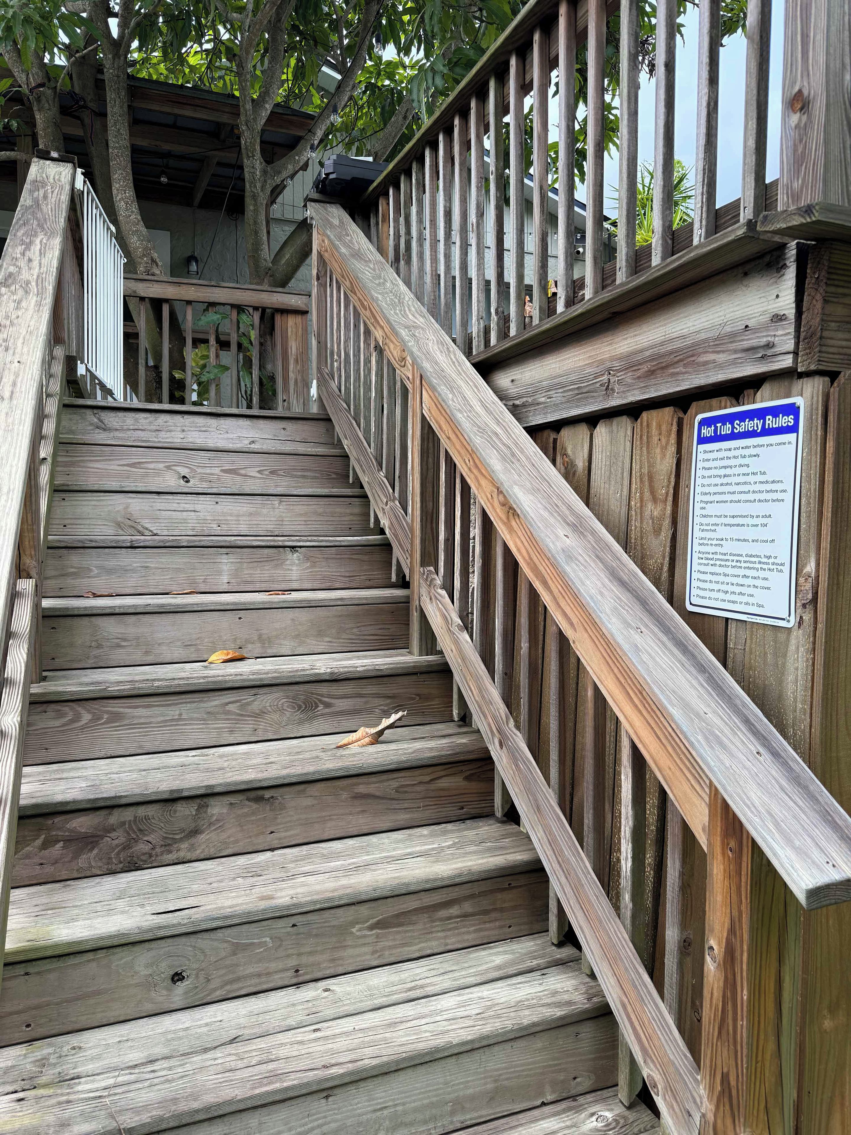 Un escalier en bois, agrémenté d’un panneau de sécurité, entouré d’arbres.