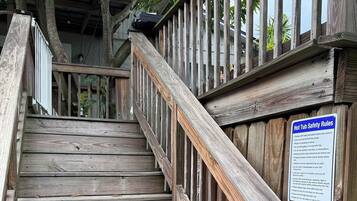 Un escalier en bois, agrémenté d’un panneau de sécurité, entouré d’arbres.
