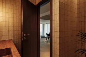 A modern bathroom with a wooden door, tiled walls, and a marble countertop. - Linum Hill Luxury 2BR Apt Ensuite Baths & Pool (Agios Nikolaos)