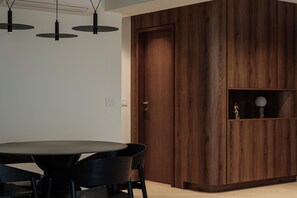 Un intérieur moderne avec une table de salle à manger ronde, des chaises noires et un meuble en bois doté d’une étagère en verre.