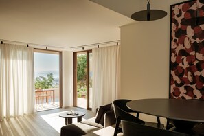 Quarto moderno com mesa de jantar, cadeiras, sofá e vista para o exterior.