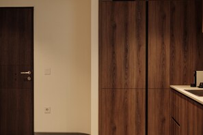 Une pièce avec une armoire en bois, un mur blanc et une porte dotée d’une poignée.