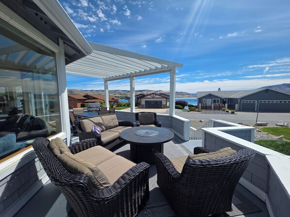 A covered patio with wicker furniture, a grill, and a view of a lake and mountains. - Wapato Point Family Oasis Sleeps 12 w/Private Buoy, Hot Tub, 6 Bedrooms 5.5 Bath (Manson)