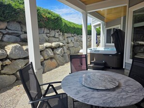 Eine Außenpatio mit Steinmauer, Whirlpool und runder Marmortisch mit Stühlen.