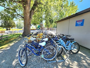 A bicycle parking area with multiple bicycles, a picnic table, and a sign for the Kiosk Recreation Center.