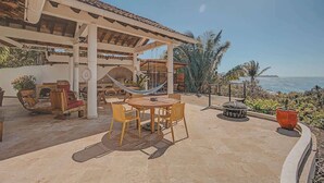An outdoor patio with a round table and chairs, a hammock, and a fire pit. - Villa Catalina - Pool - OceanViews - 5 King Suites (San Francisco)